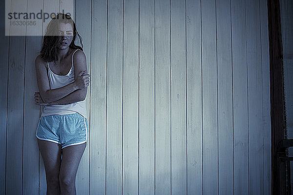 Traurige junge Frau im Schlafzimmer stehend