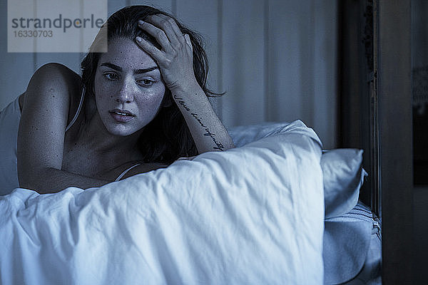 Traurige junge Frau auf dem Bett liegend