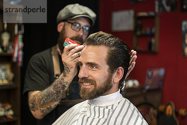 Friseurin stylt Haare eines Mannes im Salon