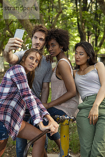 Junge Freunde stehen auf der alten Plattform des Karussells und machen ein Selfie