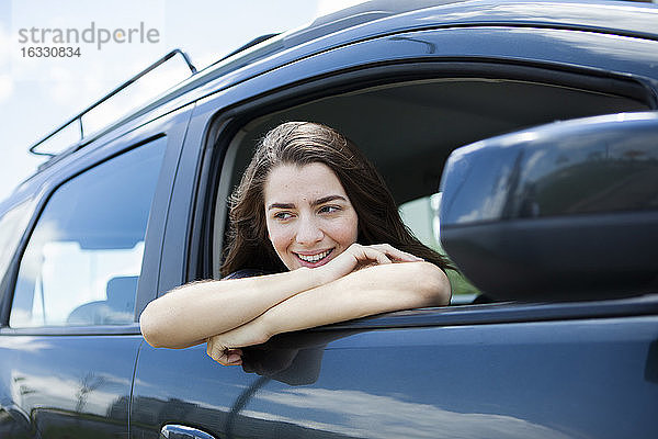 Schöne lächelnde junge Frau sitzt im Auto