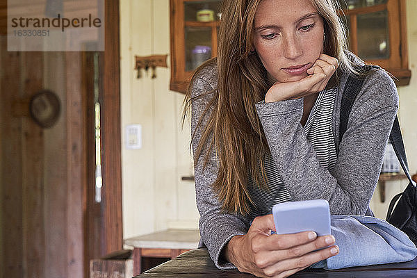 Junge Frau benutzt Smartphone zu Hause