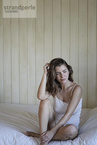 Schöne junge Frau auf dem Bett sitzend