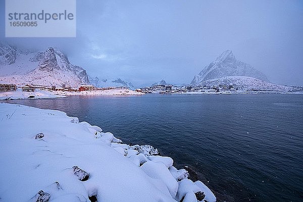 Winterliche Stimmung am Fjord  frühmorgens im Fischerdorf  Schneefall in den Bergen  Reine  Nordland  Lofoten  Norwegen  Europa