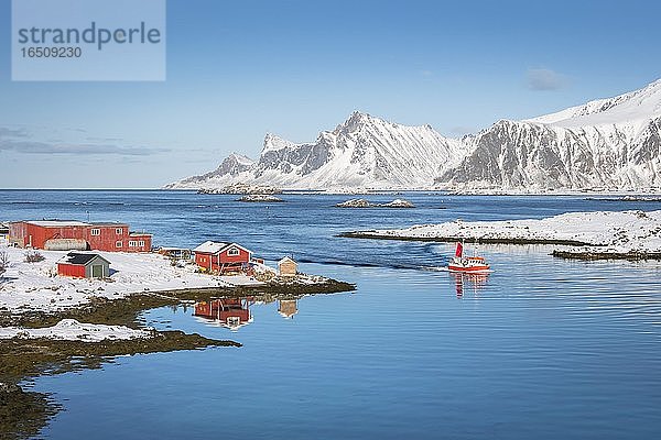 Rotes Farmhaus und Fischerboot spiegeln sich im Fjord Rossoy Straumen  hinten weiter Ozean  verschneite Berge Hustinden und Björntinden  Nordland  Lofoten  Norwegen  Europa