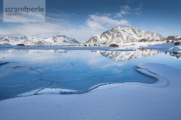 Türkise Lagune mit Schneefläche und Eisschollen  dahinter schneebedeckte Berge Sundklakktinden und Varden Anderstinden  Nordland  Lofoten  Norwegen  Europa