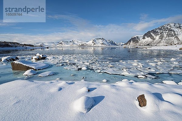Türkise Lagune mit Schneefläche und Eisschollen  dahinter schneebedeckte Berge  Nordland  Lofoten  Norwegen  Europa