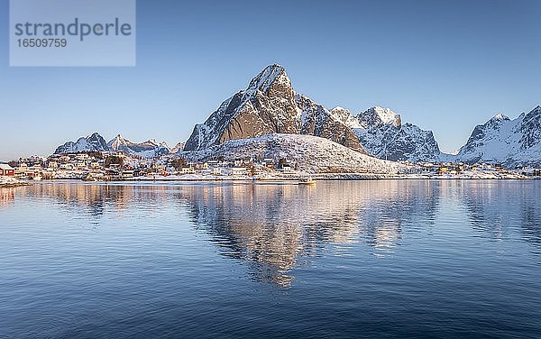 Fischerdorf spiegelt sich im Meer  hinten verschneite Berge  Reine  Nordland  Lofoten  Norwegen  Europa