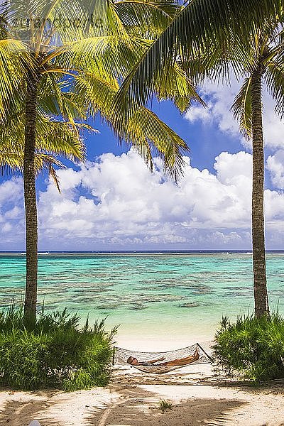 Frau entspannt sich in einer Hängematte unter Palmen am weißen Sandstrand auf der tropischen Insel Rarotonga  Cookinseln  Südpazifik