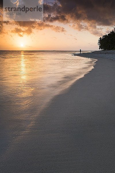Person  die den tropischen Sonnenaufgang mit dramatischen orangefarbenen Wolken über dem Pazifischen Ozean  Rarotonga Island  Cook Islands Hintergrund mit Kopie Raum