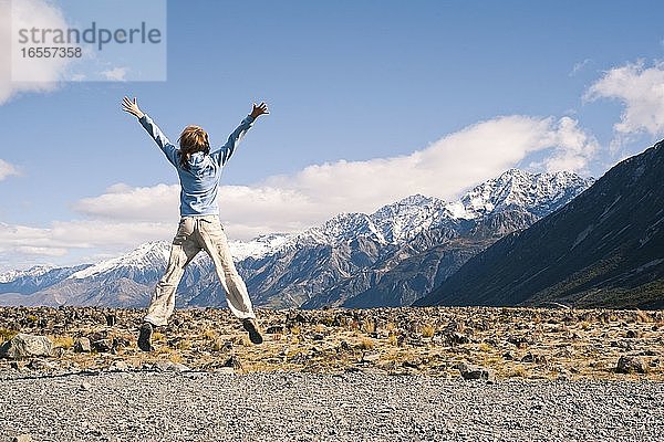 Junge Frau  die vor Freude springt  im Aoraki Mount Cook National Park  Südinsel  Neuseeland