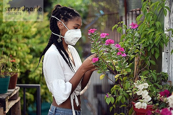 Junge Frau mit Gesichtsmaske bei der Gartenarbeit