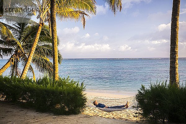 Frau entspannt sich in einer Hängematte unter Palmen am weißen Sandstrand auf der tropischen Insel Rarotonga  Cookinseln  Südpazifik