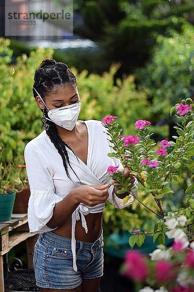Junge Frau mit Gesichtsmaske bei der Gartenarbeit