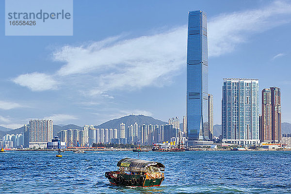 Hongkong  China. Hongkong  China. Blick über den Victoria Harbour auf den Wolkenkratzer des International Commerce Centre in Kowloon. Das Gebäude ist 118 Stockwerke hoch. Traditionelles Arbeitsboot im Vordergrund.