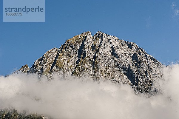 Wolken über den Berggipfeln am Milford Sound  Fiordland  Südinsel  Neuseeland. Die Berge  die sich auf beiden Seiten des Milford Sound bis zu 1500 m hoch auftürmen  sind sehr beeindruckend  vor allem  wenn Sie das Glück haben  einen der 180 Regentage im Jahr zu vermeiden!