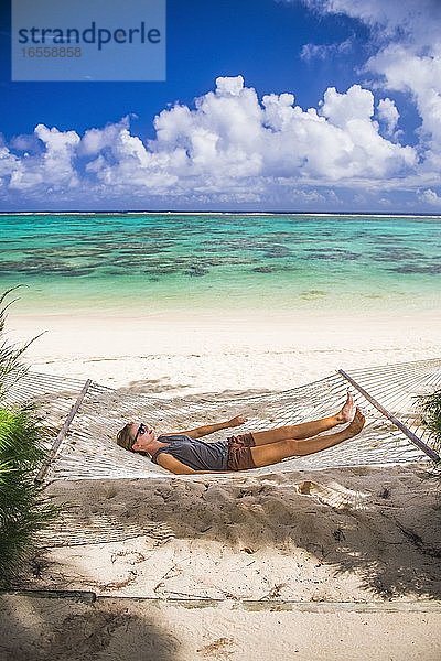 Frau entspannt sich in einer Hängematte unter Palmen am weißen Sandstrand auf der tropischen Insel Rarotonga  Cookinseln  Südpazifik