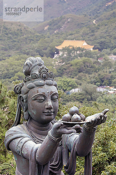 Hongkong  China. Po Lin-Kloster  Insel Lantou. Statue eines Deva  der dem Großen Buddha Früchte opfert.
