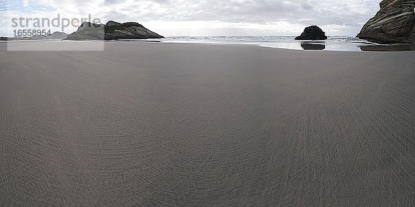 Panoramafoto des verlassenen Wharariki Beach  Golden Bay  Südinsel  Neuseeland. Dieses Panoramafoto zeigt den Wharariki Beach  einen bemerkenswerten  abgelegenen  verlassenen Strand  der durch starke  treibende Winde verwittert ist und sich im Norden der Südinsel Neuseelands in der Golden Bay Area befindet.