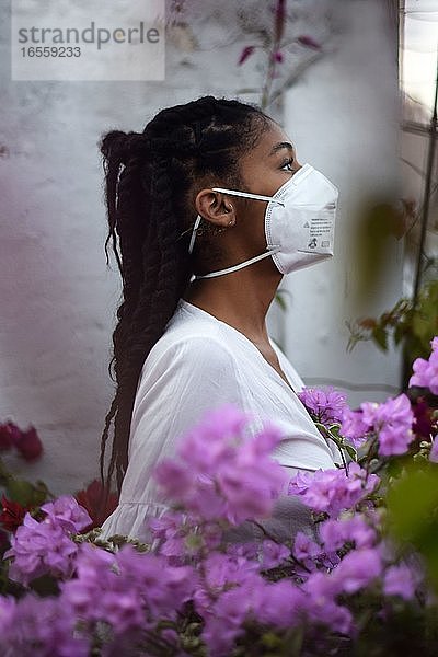 Junge schwarze Frau mit Gesichtsmaske auf dem Balkon