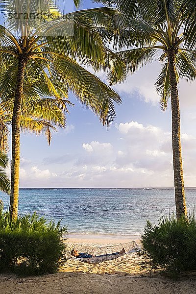 Frau entspannt sich in einer Hängematte unter Palmen am weißen Sandstrand auf der tropischen Insel Rarotonga  Cookinseln  Südpazifik