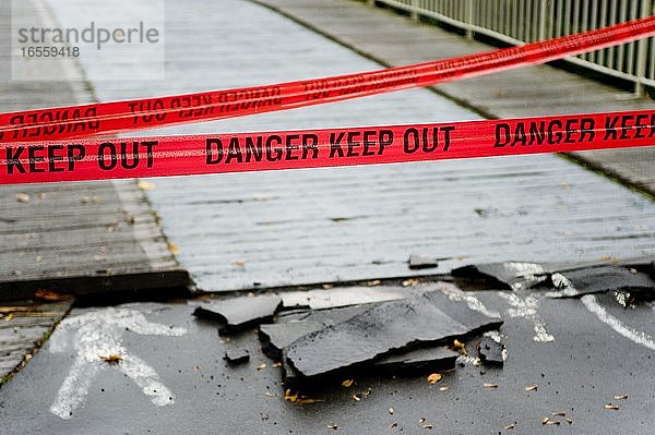 Ein rotes Band mit der Aufschrift Gefahr im Verzug hindert Menschen daran  eine Brücke zu überqueren. Aufgenommen in Christchurch nach dem Erdbeben vom 22. Februar 2011.