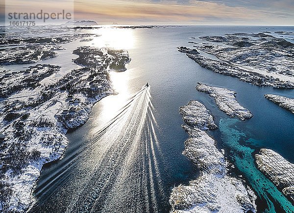 Motorboot fährt durch eine winterliche Fjordlandschaft mit kleinen Inseln  Herøy  Nordland  Norwegen  Europa