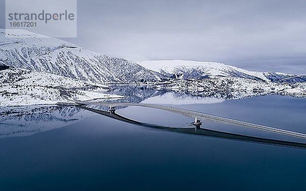 Lange Autobrücle über einem spiegelglattem blauen Fjord in winterlicher Landschaft  Gildeskål  Nordland  Norwegen  Europa