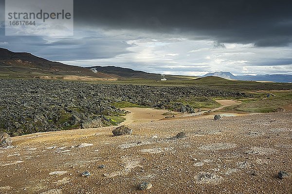 Schwarzer Lavastrom im Krafla Lavafeld mit Geothermalkraftwerk in der Ferne  Skútustaðir  Norðurland eystra  Island  Europa