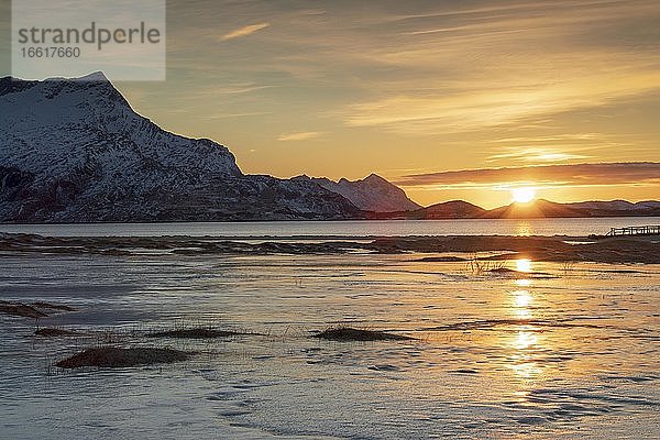 Sonnenuntergang an mit Eisschicht bedecktem Sandstrand  hinten Berge  Langsanden Strand  Nordland  Norwegen  Europa