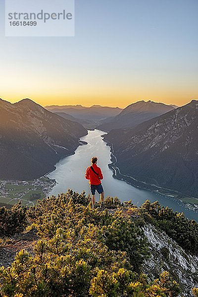 Sonnenuntergang  junger Mann blickt über Berglandschaft  Ausblick vom Gipfel des Bärenkopf auf den Achensee  links Seebergspitze und Seekarspitze  Tirol  Österreich  Europa