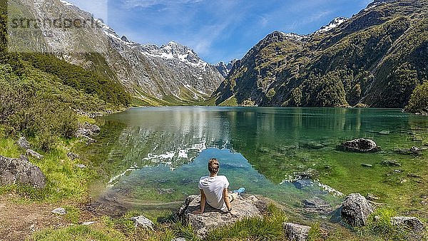 Wanderer sitzt am Ufer  Lake Marian  Fiordland Nationalpark  Te Anau  Southland  Südinsel  Neuseeland  Ozeanien