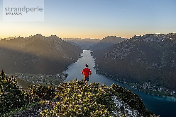 Sonnenuntergang  junger Mann blickt über Berglandschaft  Ausblick vom Gipfel des Bärenkopf auf den Achensee  links Seebergspitze und Seekarspitze  rechts Rofangebirge  Tirol  Österreich  Europa