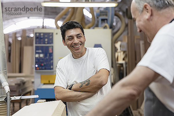 Lächelnde Mitarbeiter bei der gemeinsamen Arbeit in der Werkstatt