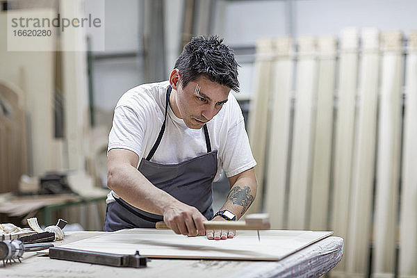 Künstlerin  die in der Werkstatt stehend Holz mit traditionellen Methoden gestaltet
