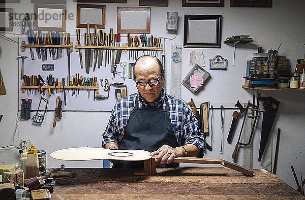 Ein erfahrener Geigenbauer fertigt eine Gitarre in der Werkstatt