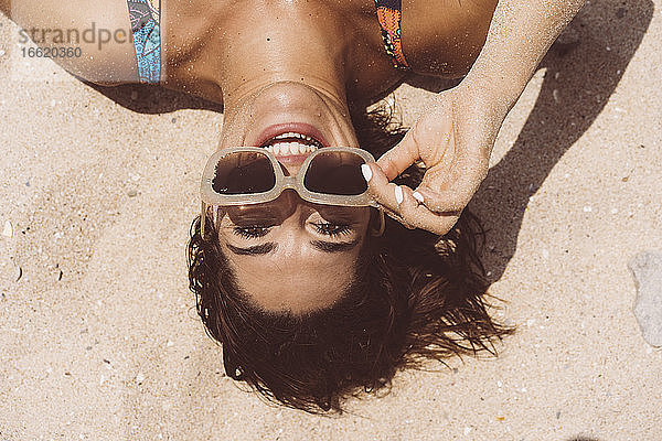 Fröhliche Frau mit Sonnenbrille am Strand von Valdevaqueros an einem sonnigen Tag  Tarifa  Spanien