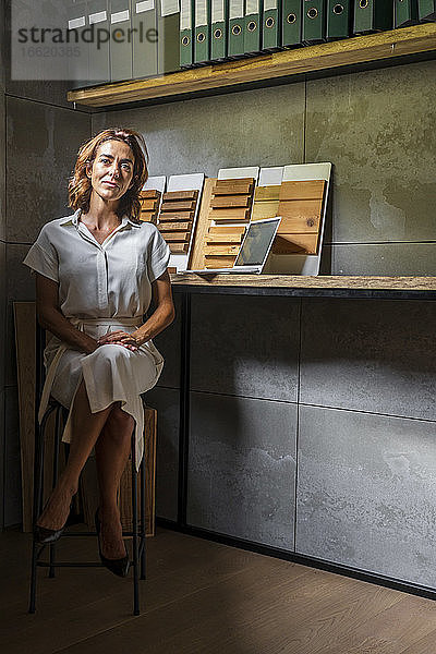 Geschäftsfrau mit Holzfliesen sitzt am Schreibtisch im Büro