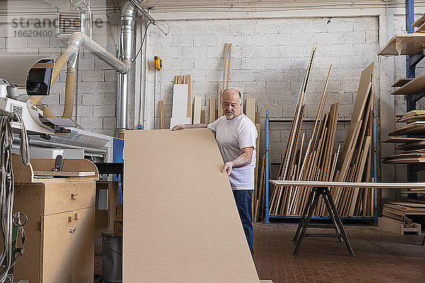 Mann  der eine Holzschneidemaschine bedient  während er in einer Fabrik steht