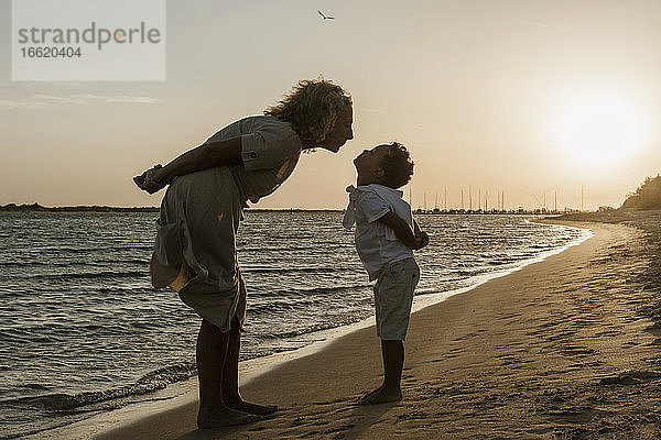 Enkel und Großmutter küssen Geste am Strand bei Sonnenuntergang