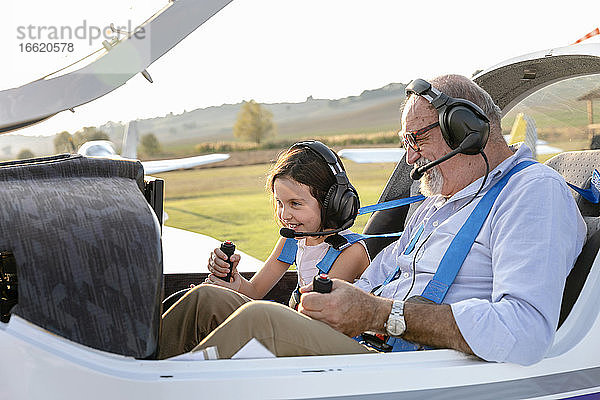 Enkelin sitzt mit Großvater im Flugzeug auf dem Flugplatz