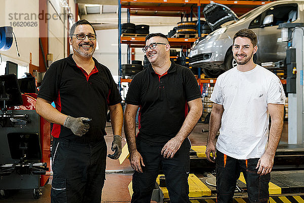 Lächelnde männliche Mitarbeiter in einer Autowerkstatt