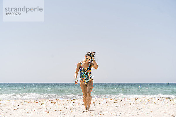 Frau mit Bodysuit und Sonnenbrille beim Spaziergang am Strand von Valdevaqueros  Tarifa  Spanien