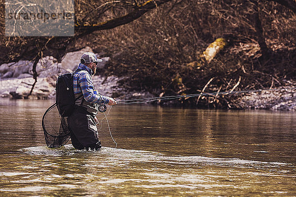 Fischer steht im Fluss und fängt Fische an einem sonnigen Tag