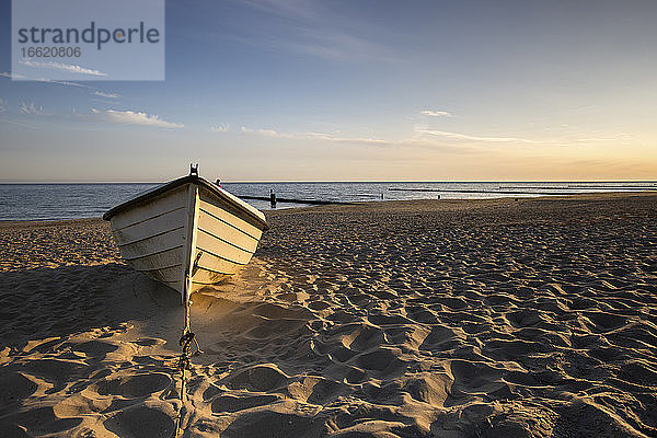 Boot in der Morgendämmerung am Sandstrand liegen gelassen