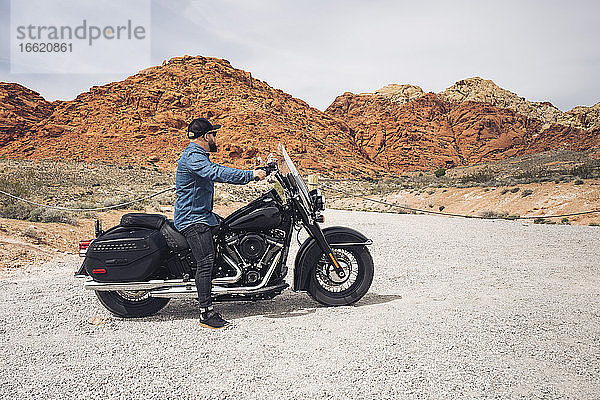 Mann sitzt auf einem Motorrad im Valley of Fire State Park  Nevada  USA
