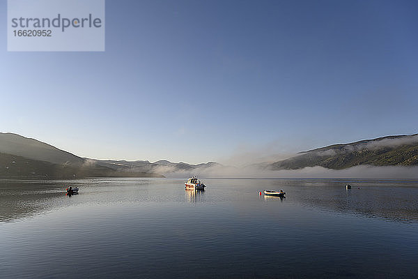 UK  Schottland  Ullapool  Klarer Himmel über Booten im Loch Broom bei nebligem Wetter