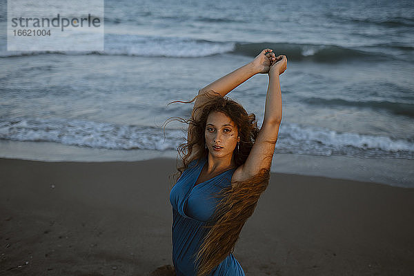 Schöne junge Frau tanzt am Strand