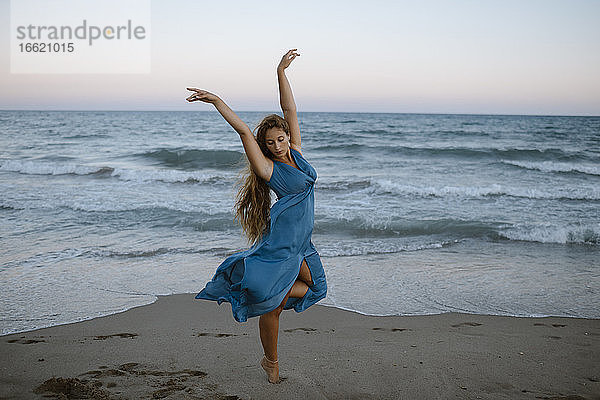 Junge Frau tanzt gegen das Meer am Strand