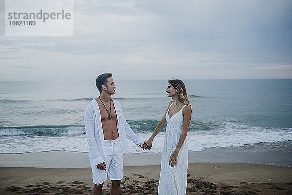 Junges Paar schaut sich am Strand stehend an